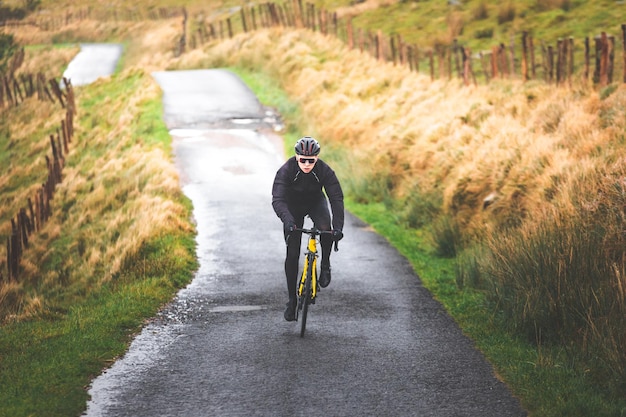 Jeune homme cycliste caucasien escaladant une colline dans une montagne brumeuse.