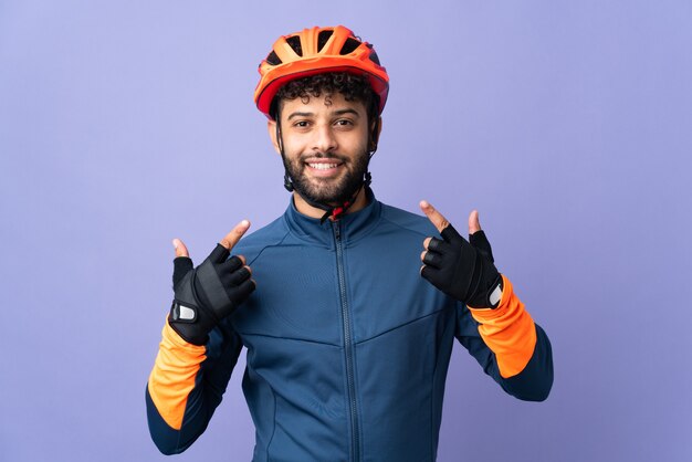 Jeune homme cycliste marocain isolé sur mur violet donnant un geste de pouce en l'air