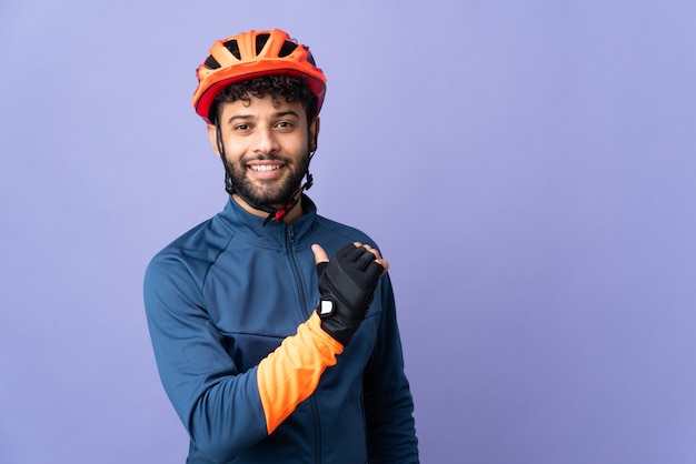 Jeune homme cycliste marocain isolé sur mur violet fier et satisfait de soi