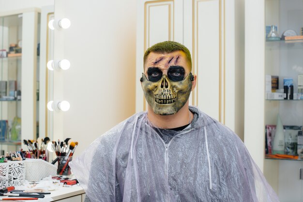 Un jeune homme dans un beau maquillage effrayant sous la forme d'un crâne pour les vacances d'Halloween en gros plan de studio. Concept d'Halloween heureux.