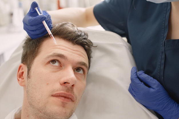 Un jeune homme dans un cabinet de cosmétologue a une injection faciale pour le levage