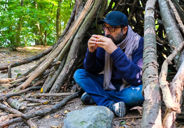 Jeune homme dans la forêt buvant du café sous un abri avec bluecap
