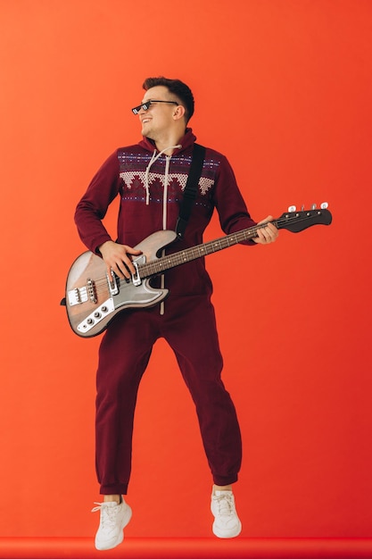 Un jeune homme dans un kigurumi de Noël joue de la guitare électrique sur un fond coloré