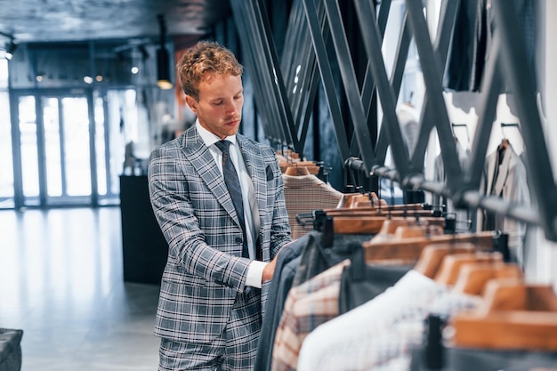 Jeune homme dans un magasin moderne avec de nouveaux vêtements Vêtements élégants et chers pour hommes