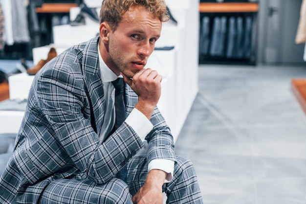 Jeune homme dans un magasin moderne avec de nouveaux vêtements Vêtements élégants et chers pour hommes