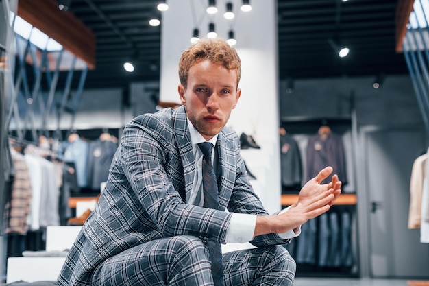 Jeune homme dans un magasin moderne avec de nouveaux vêtements Vêtements élégants et chers pour hommes