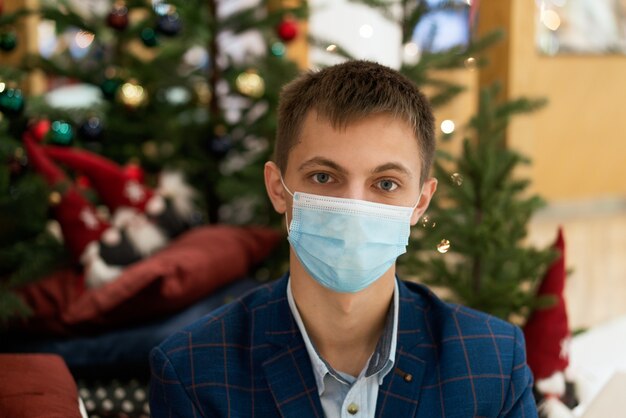 Un jeune homme dans un masque sur le fond d'un arbre de Noël