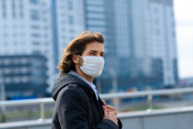 Jeune homme dans un masque médical à l'extérieur, pas d'argent, crise, pauvreté, difficultés. Isolement lié au coronavirus.