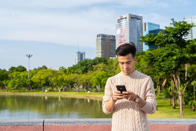 Jeune homme dans le parc pendant l'été à l'aide de téléphone