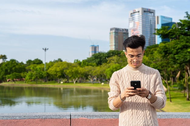 Jeune homme dans le parc pendant l'été à l'aide de téléphone