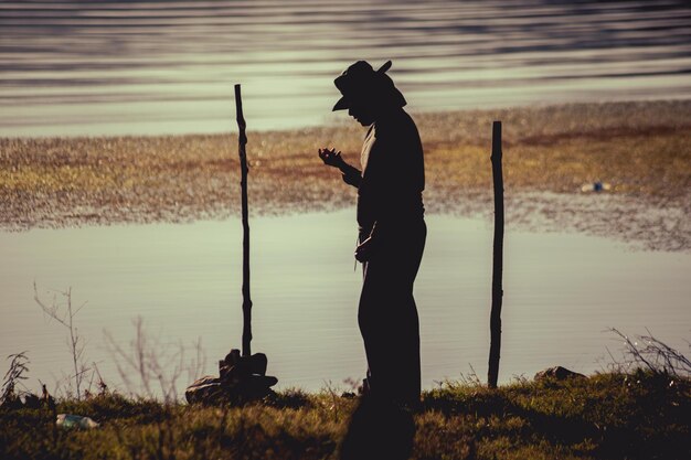 Photo jeune homme dans la rivière avec chapeau de pêcheur