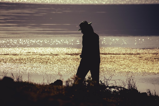 Jeune homme dans la rivière avec chapeau de pêcheur