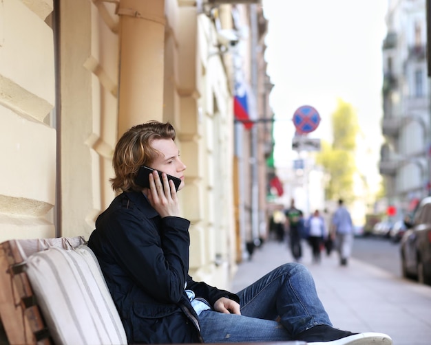 un jeune homme dans une rue de la ville en utilisant un smartphone