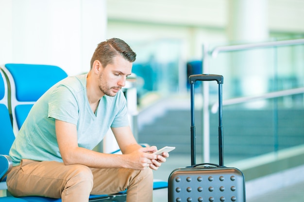 Jeune homme dans un salon d'aéroport en attente d'avion de vol.