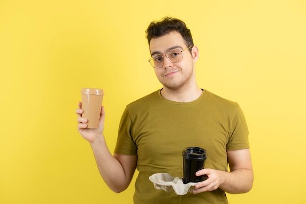 jeune homme dans des verres tenant deux tasses de café.