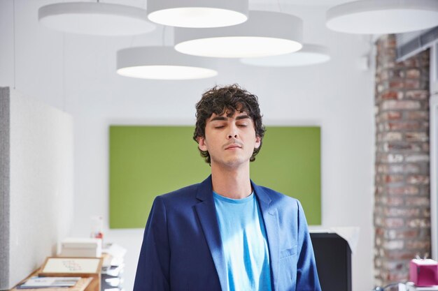 jeune homme debout au bureau avec les yeux fermés