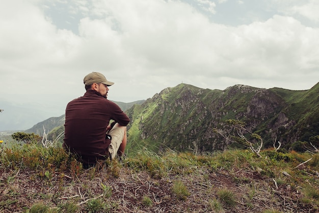 Jeune homme debout au sommet de la falaise dans les montagnes