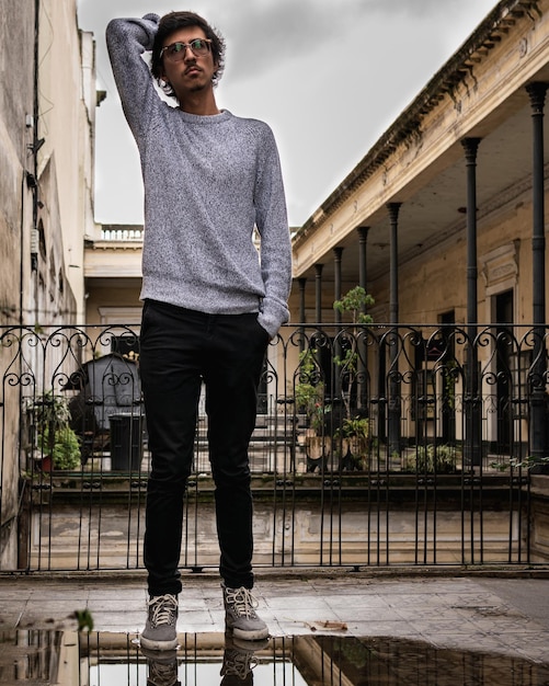 Un jeune homme debout contre la balustrade.