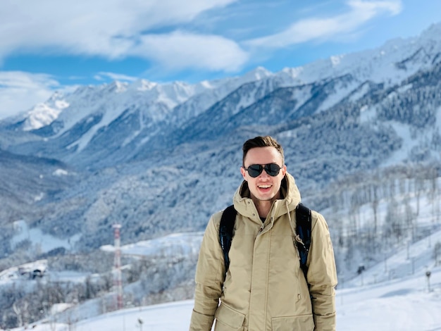 Un jeune homme debout contre des montagnes enneigées
