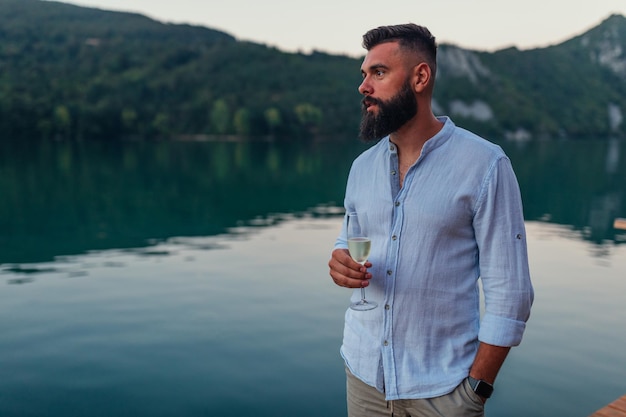 Jeune homme debout à côté de la rivière et buvant du champagne