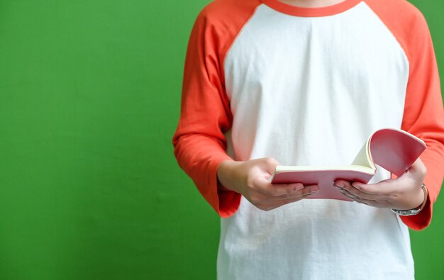 Jeune homme debout et lecture de livre en face de fond de mur végétalisé avec espace copie, éducation de fond