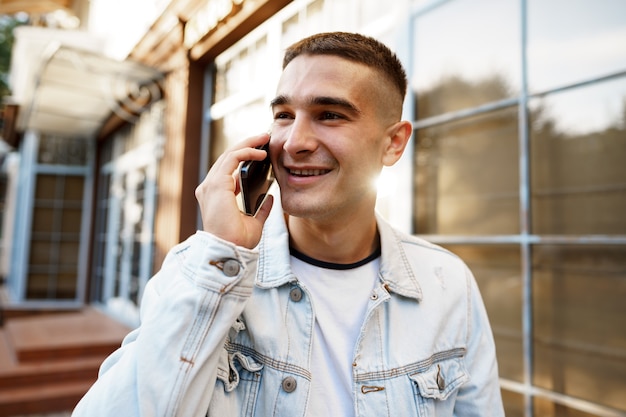 Jeune homme décontracté marchant dans la rue et parlant au téléphone portrait en gros plan