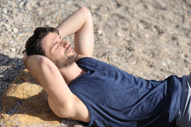 Jeune homme détendu portrait en plein air, allongé sur un sable