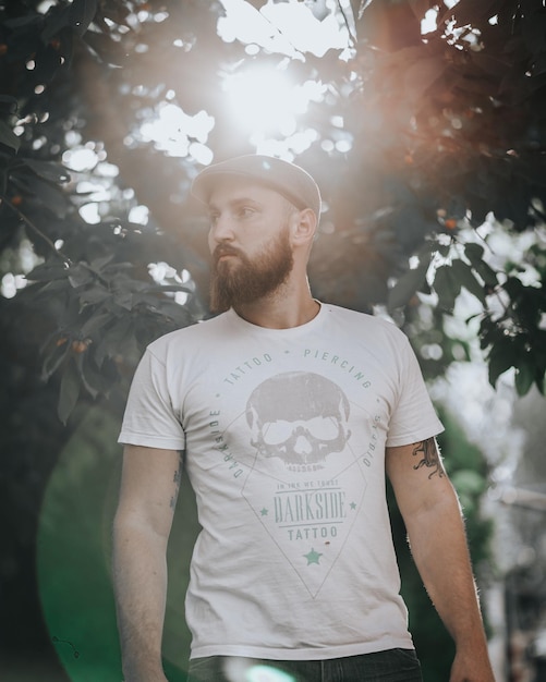 Un jeune homme détournant les yeux alors qu'il se tient contre les arbres.