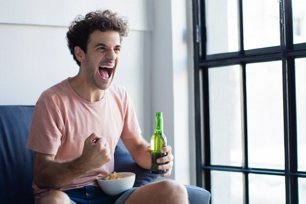 Jeune homme devant la télé sur le canapé.