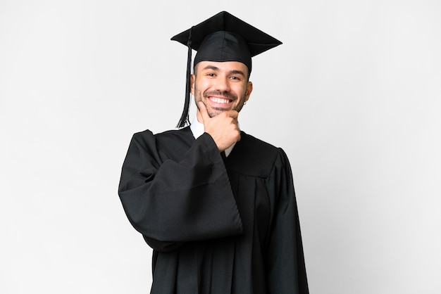 Jeune homme diplômé universitaire sur fond blanc isolé souriant