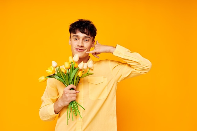 Un jeune homme donne des fleurs porte des lunettes chemise jaune fond jaune inaltéré