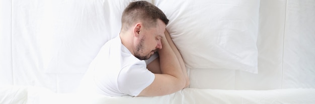 Jeune homme dort paisiblement sur un grand lit blanc concept de sommeil sain