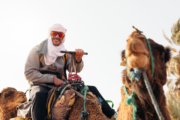 Jeune homme à dos de dromadaire dans le désert du Sahara.