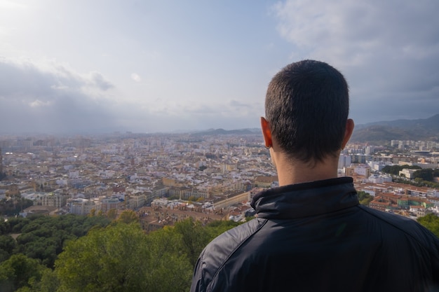 Jeune homme de dos regardant la ville de Malaga.