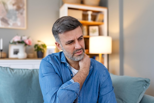 Photo un jeune homme avec une douleur à l'épaule un homme tenant son épaule douloureuse un homme tenant sa main l'échafaudant souffrant d'une douleur aux épaules souffrant de douleur à la main à la maison