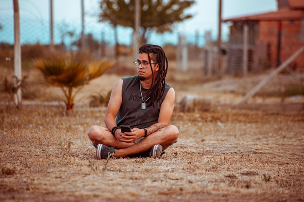 Jeune homme avec des dreadlocks assis sur le sol