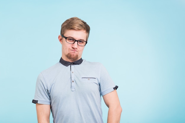 Jeune homme drôle porte des lunettes isolées sur bleu