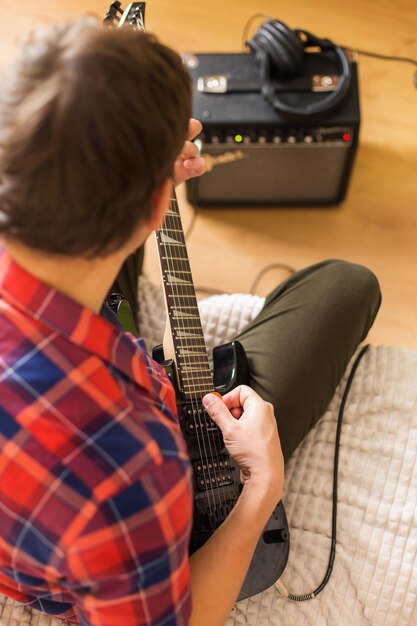 Jeune homme du millénaire jouant de la guitare électrique Rester à la maison cours d'apprentissage de l'activité à la maison