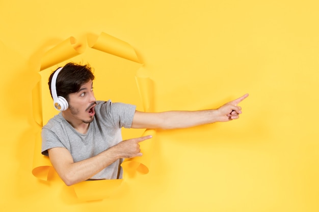 jeune homme écoutant de la musique dans des écouteurs sur fond jaune déchiré échographie audio sonore