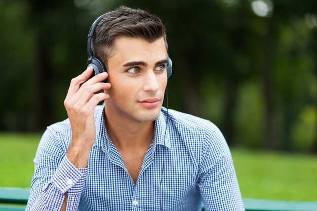 Jeune homme écoutant de la musique dans un parc de la ville