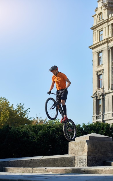 Jeune homme effectuant un vélo de montagne radical saute dans la vieille ville