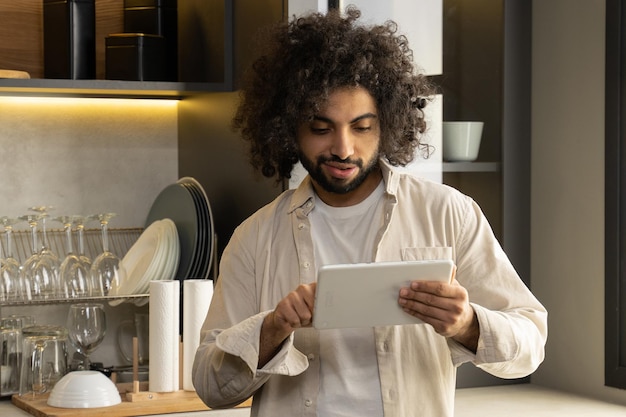 Un jeune homme égyptien commande de la nourriture via une tablette dans la cuisine de la maison