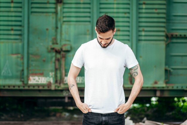 Jeune homme élégant avec une barbe dans un T-shirt blanc et des lunettes