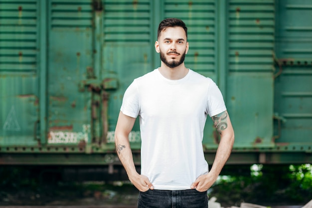 Jeune homme élégant avec une barbe dans un T-shirt blanc et des lunettes