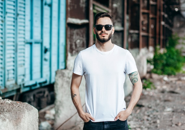 Jeune homme élégant avec une barbe dans un T-shirt blanc et des lunettes