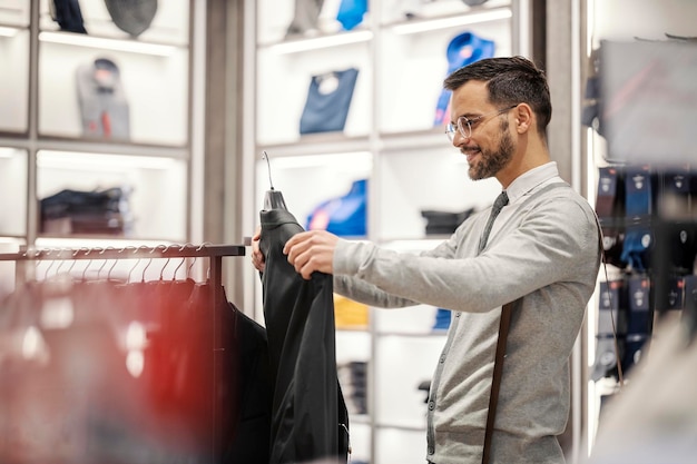 Un jeune homme élégant choisit le costume au magasin