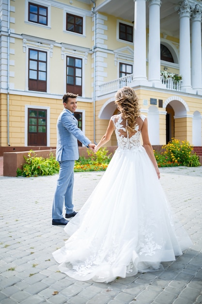 Jeune homme élégant en costume le marié et la mariée belle fille en robe blanche avec une promenade en train dans le parc le jour de leur mariage