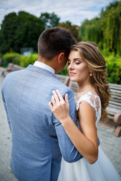 Jeune homme élégant en costume le marié et la mariée belle fille en robe blanche avec une promenade en train dans le parc le jour de leur mariage