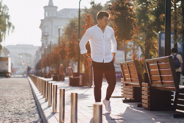 Jeune homme élégant dans une chemise en descendant une rue européenne par une journée ensoleillée