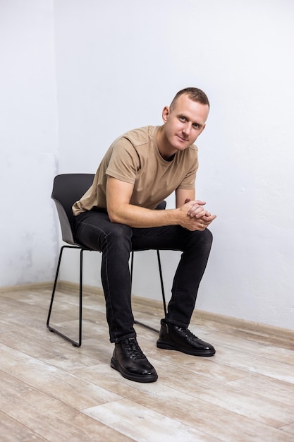 Jeune homme élégant dans un T-shirt beige et un jean noir en bottes avec du cuir noir naturel. Collection de chaussures pour hommes